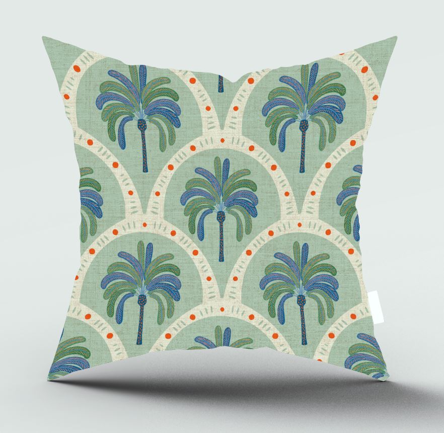 A square throw pillow featuring a retro bohemian palm tree pattern in shades of blue, green, and orange on a sage green and cream background, shown against a neutral gray studio backdrop.