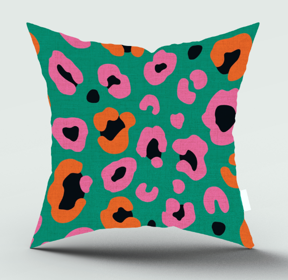 A square throw pillow with a vibrant green background and a bold leopard-style print in pink, orange, and black, shown against a light gray background.