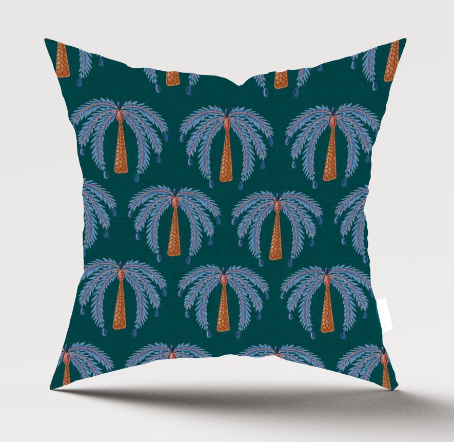 A square throw pillow featuring a repeating palm tree pattern on a dark teal background, with light blue-gray fronds and orange trunks, shown against a light gray studio background.