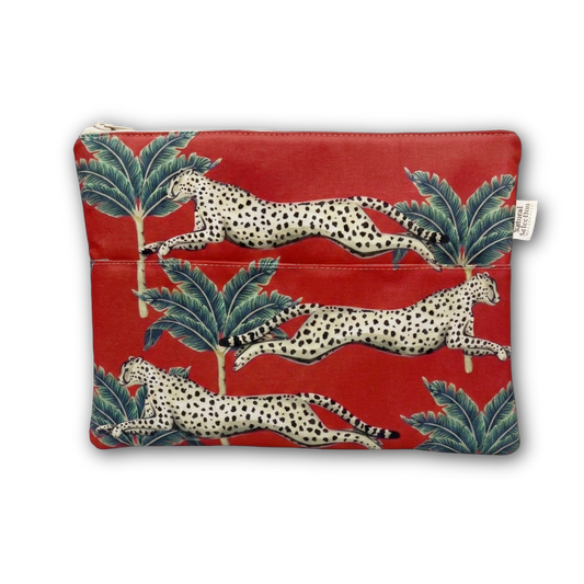 A red zippered pouch featuring a pattern of leaping cheetahs and green palm trees, with a small white brand tag on the right side.
