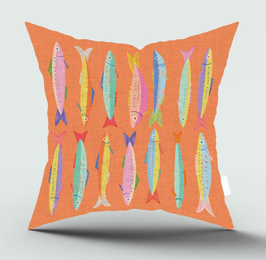 An orange throw pillow featuring a colorful pattern of illustrated fish in pink, yellow, blue, and green, shown against a neutral light gray background.