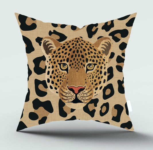 A square throw pillow featuring a printed leopard face and leopard print pattern on a light beige background, shown against a neutral gray studio backdrop.