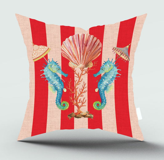 A square throw pillow featuring a vibrant red and beige striped background with a central underwater theme illustration of two blue seahorses, a pink seashell, coral, and small parasols, shown on a light gray background.