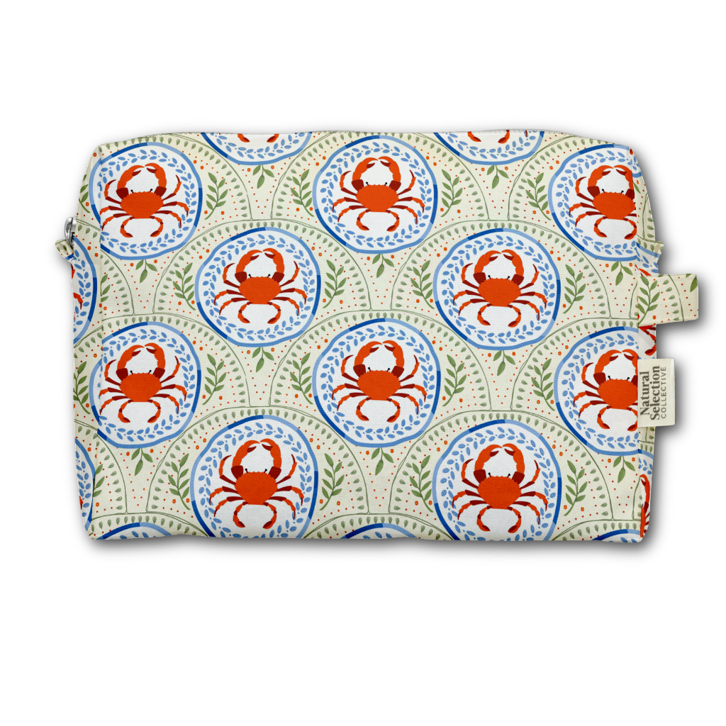 A rectangular zippered pouch with a repeating crab and medallion pattern in orange, blue, green, and cream, shown on a plain white background. A fabric tag on the right side reads 'Savages'.