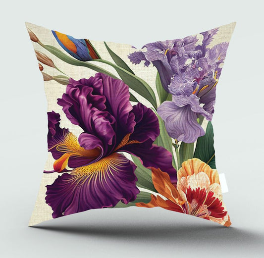 Square decorative throw pillow featuring a vibrant floral print with purple irises, an orange-red tulip, green leaves, and a small blue bird on a light beige linen-textured background, shown against a neutral light gray studio backdrop.