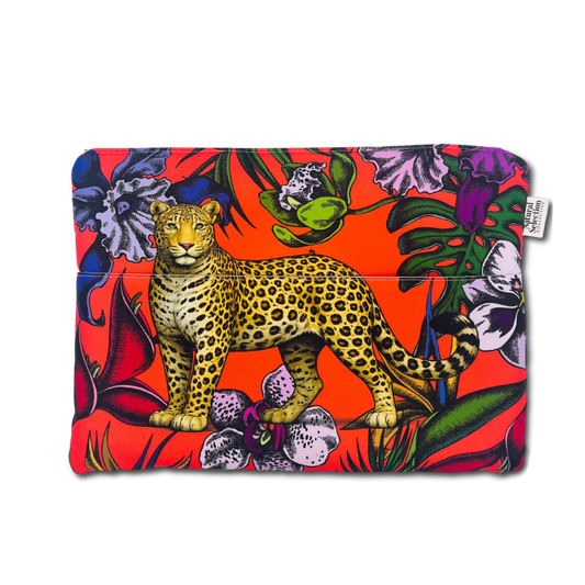 A laptop sleeve featuring a vibrant tropical print with a central leopard illustration, set against a bright red background with purple flowers and green leaves. A small white brand tag is visible on the right side.