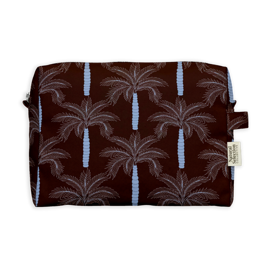 Heliopolis Palm Toiletry Bag featuring pink palm trees with pale blue trunks on chocolate brown