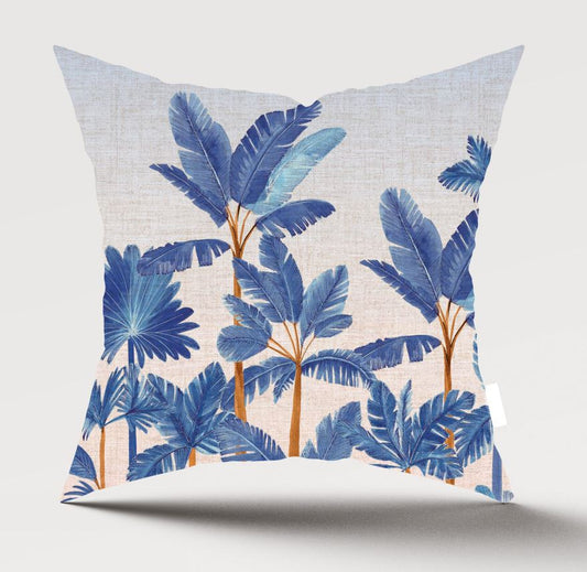 A square throw pillow featuring a tropical palm tree pattern in shades of blue and orange on a light beige linen-textured background, shown against a neutral light gray studio backdrop.