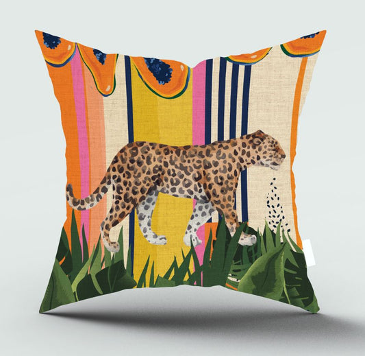A square decorative throw pillow featuring a colorful illustrated design with a leopard walking across green tropical foliage, set against vertical stripes of orange, yellow, pink, blue, and beige, with papaya slices at the top.