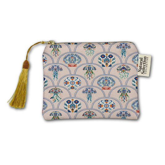 A zippered pouch with a gold tassel and a cream background featuring a repeating blue, orange, and green fan-shaped pattern. A paper brand tag reading 'Natural Selection Collective' is attached on the right side.