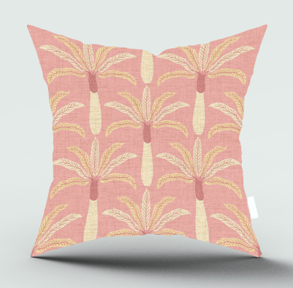 A square throw pillow with a pink linen-textured background and a repeating palm tree pattern in cream and light yellow, shown against a light gray background with a soft shadow.