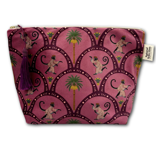 A rectangular zippered pouch with a pink and purple pattern featuring zebra-striped monkeys, palm trees, and scalloped arches. The pouch has a purple tassel zipper pull and a small white brand tag on the right side.