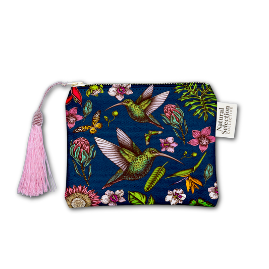 A zippered pouch featuring a dark navy blue background printed with green hummingbirds, pink flowers, and tropical leaves. The pouch has a light pink tassel zipper pull and a white fabric brand tag that reads 'Natural Selection'.
