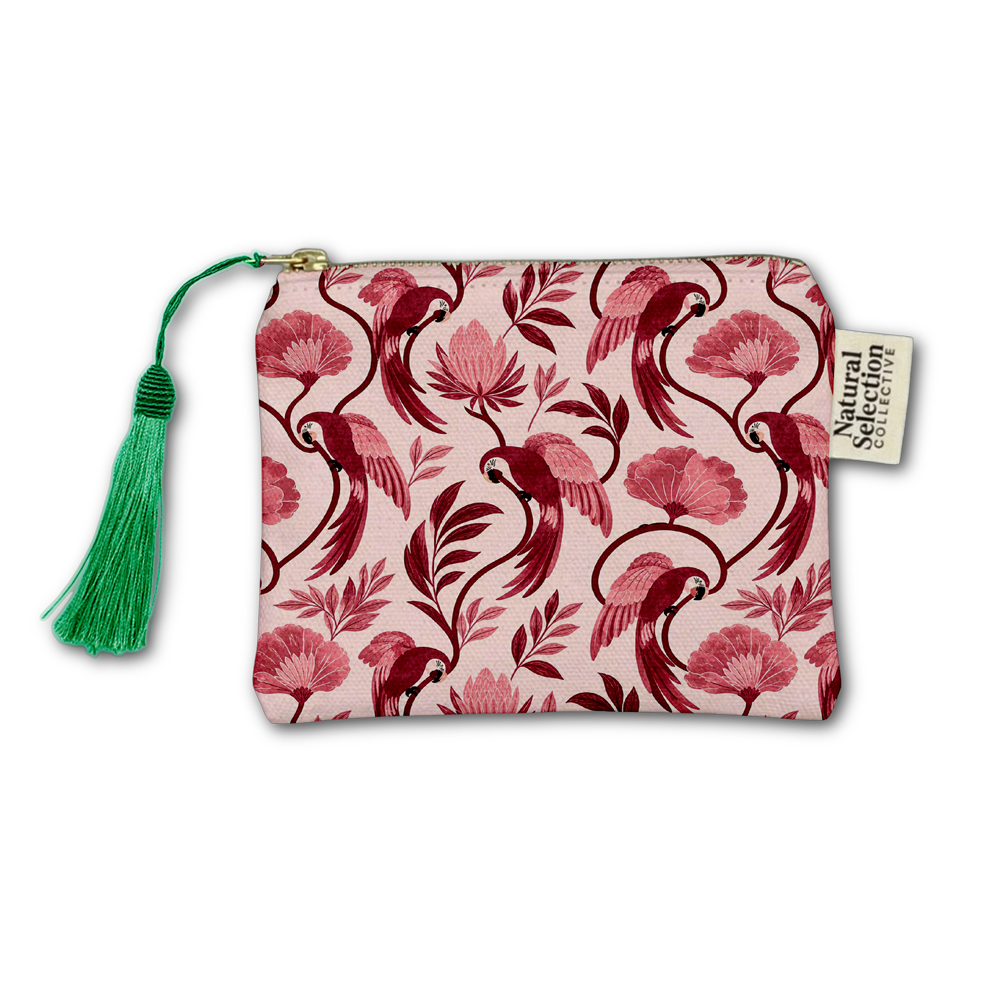 A small zip pouch with a pink and burgundy tropical parrot and floral pattern, featuring a green tassel zipper pull and a white brand tag that reads 'Natural Selection Collection'.