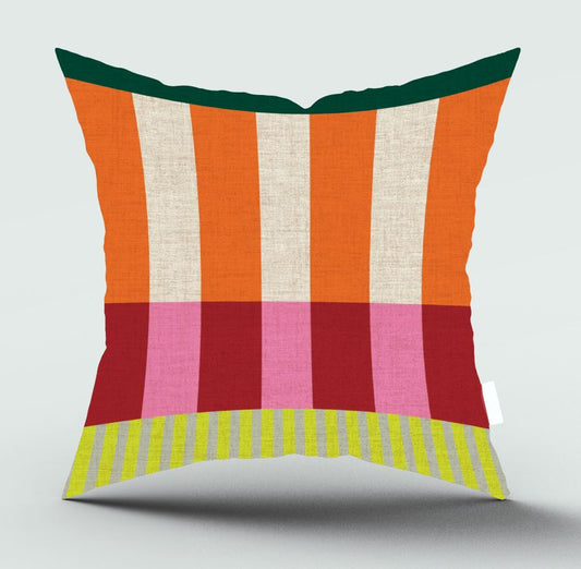 A square decorative throw pillow with a colorful striped and block pattern, featuring vertical orange, cream, and green stripes on the upper half, horizontal pink and red bands on the lower half, and a yellow and green striped border at the bottom, shown on a light gray background.