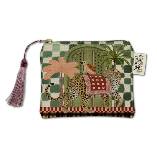 A zippered pouch featuring a whimsical safari-themed illustration with a leopard, palm trees, a bird, and a green patterned background. The pouch has a pink tassel zipper pull and a 'Natural Selection' brand tag.