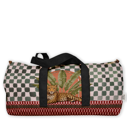A duffle bag with a complex tropical and geometric print, featuring a cheetah, palm leaves, and a checkerboard pattern in muted green, red, and beige, with black shoulder straps, shown on a plain white background.