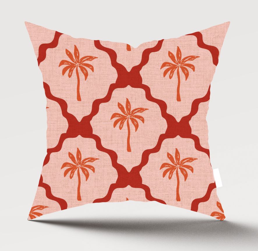 A square throw pillow with a coral pink and red geometric trellis pattern and palm tree motifs, shown against a light gray background.