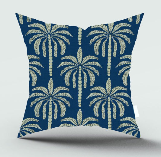 A square throw pillow with a navy blue background and a repeating cream-colored palm tree pattern, shown against a light gray background.