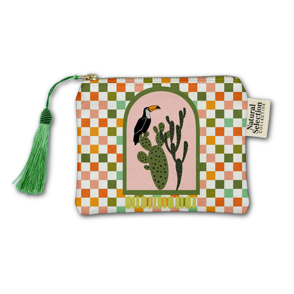 A fabric zip pouch with a colorful checkered border and a central illustration of a toucan perched on a cactus under an arch. The pouch has a green tassel zipper pull and a side tag reading 'Natural Selection Collection'.