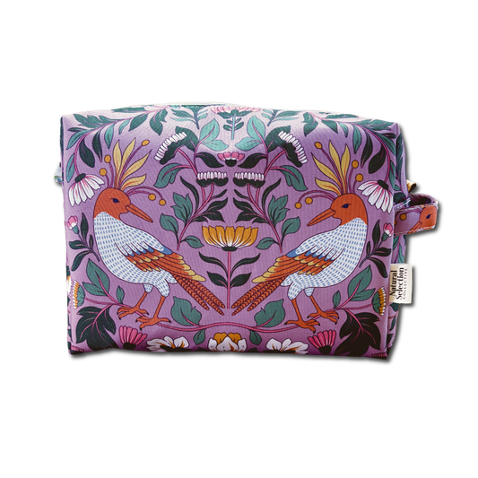 A rectangular cosmetic pouch with a symmetrical floral and bird pattern on a lavender background, featuring two stylized birds and a small side loop with a fabric tag.