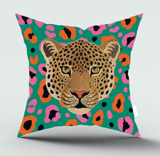 A square throw pillow featuring a stylized leopard face in the center, set against a vibrant green background with pink, orange, and black leopard spots.