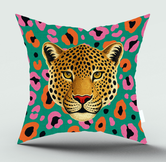 A square throw pillow featuring a stylized leopard face on a bold green background with pink, orange, and black leopard-print spots, shown against a light gray studio background.